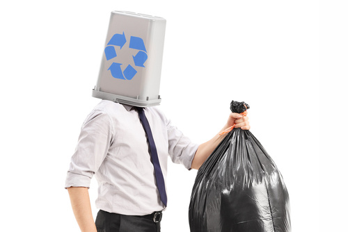 Man with a recycle bin over his head carrying a garbage bag